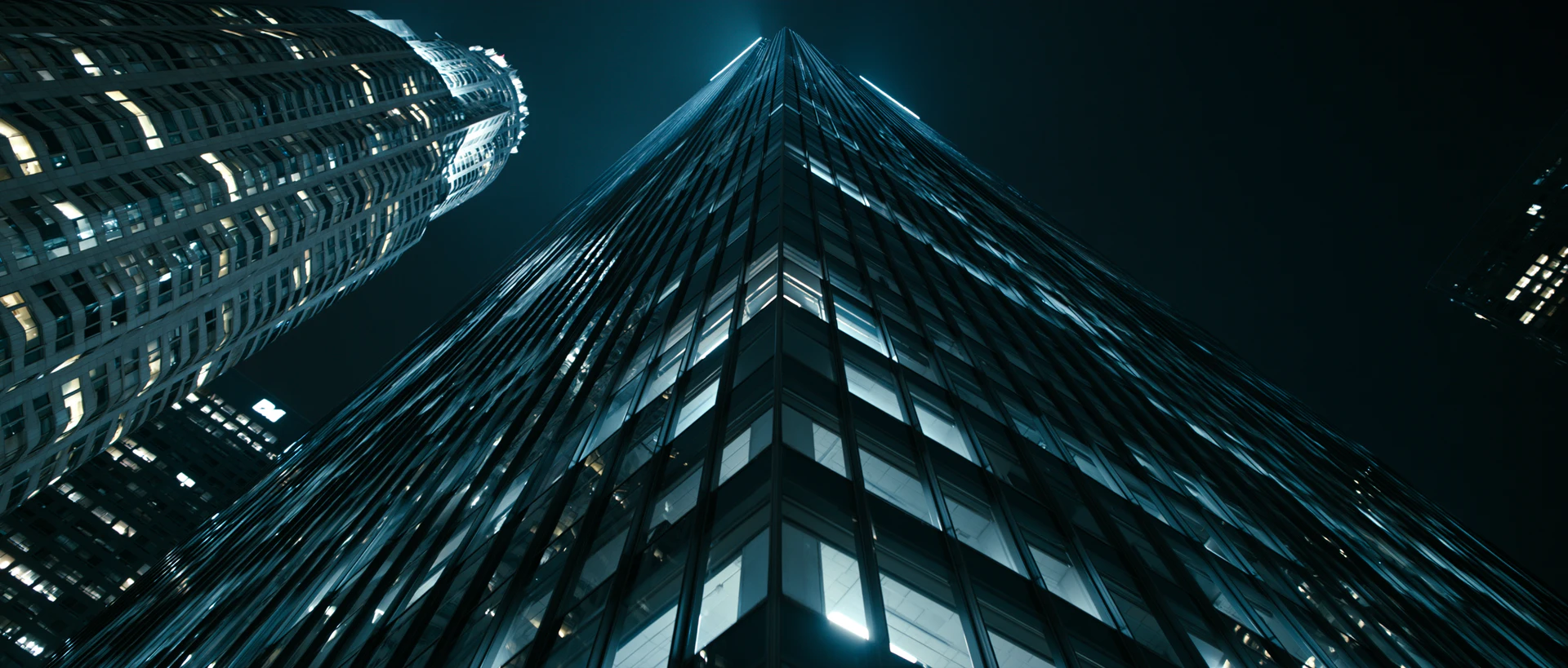 Nighttime view looking upward from the base of illuminated city towers