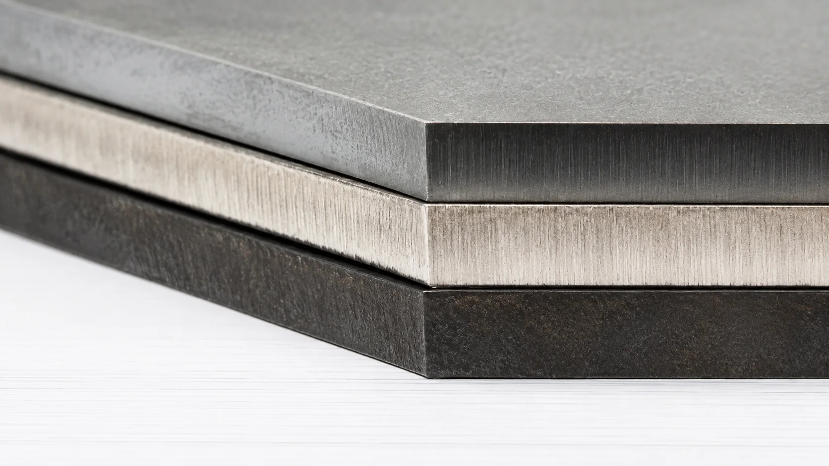 Three laser-cut metal plate edges showing different surface colors and textures